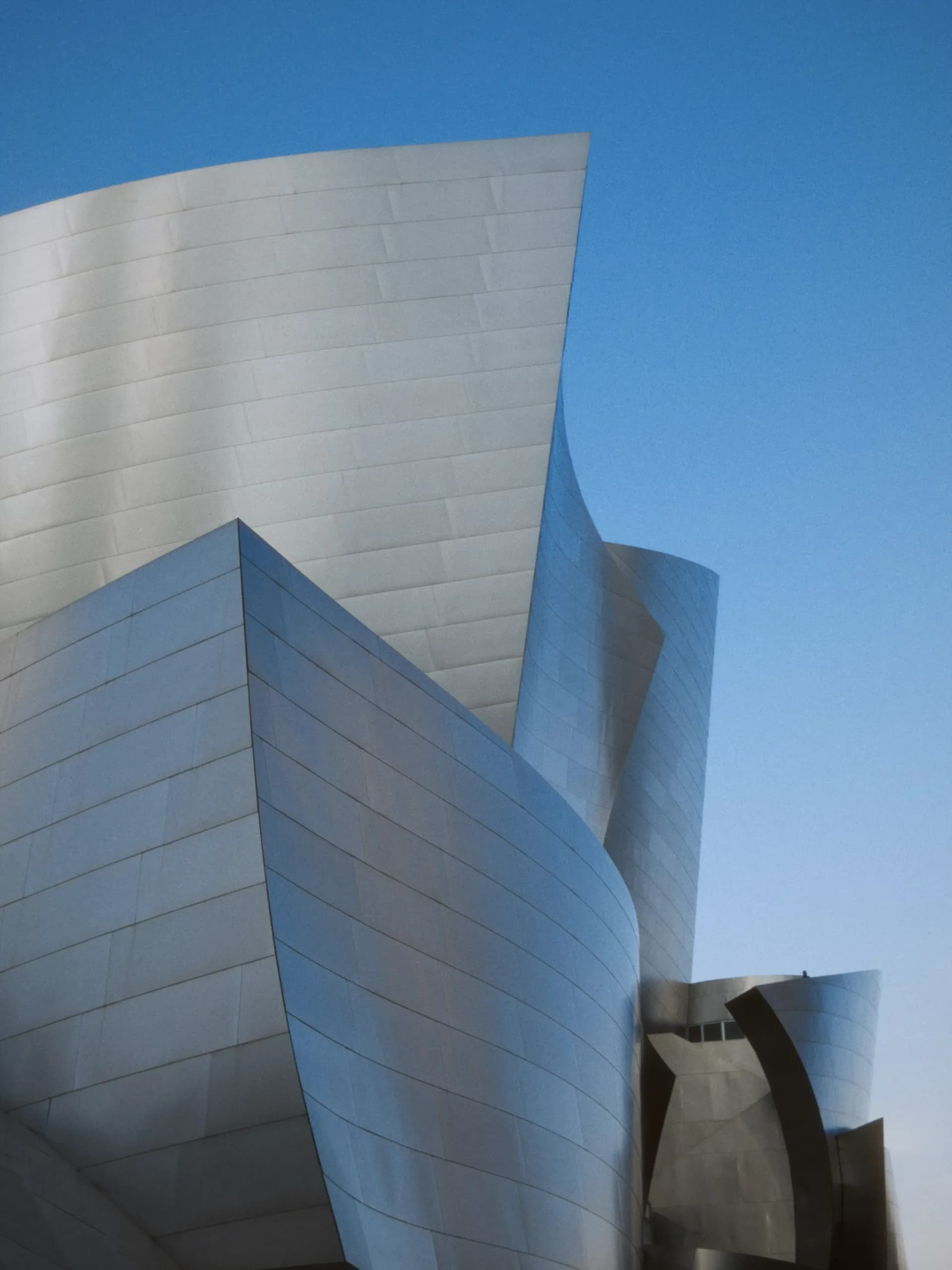 A sculptural silver building against a blue Los Angeles sky